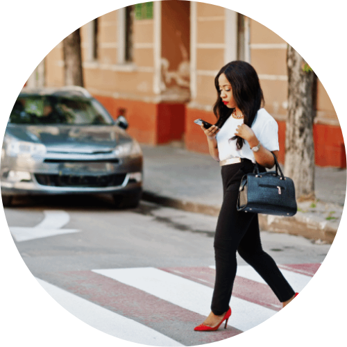 woman crossing crosswalk while looking at phone