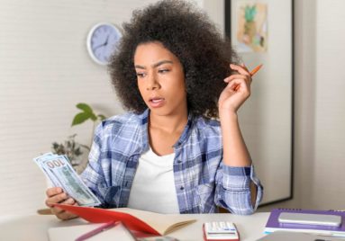 woman looking concerned at money she is holding