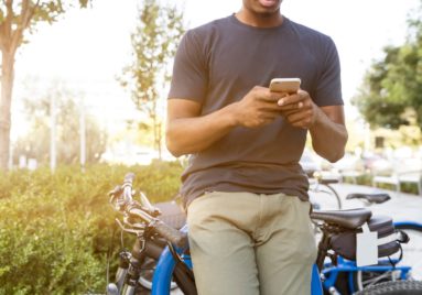 man leaning on bike while texting