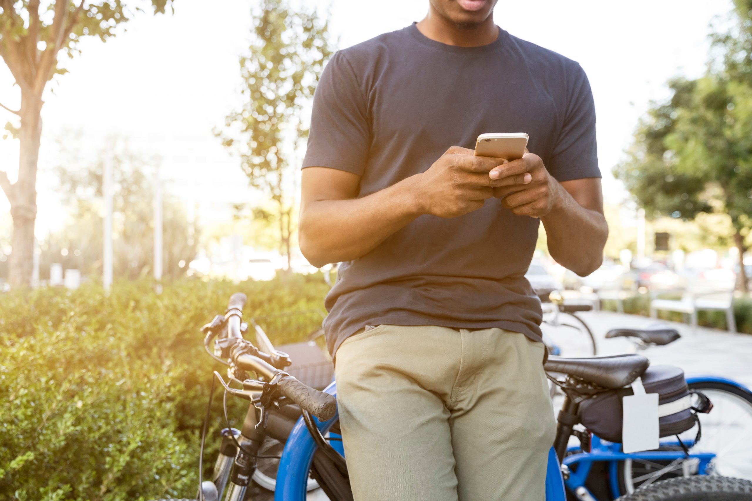 man leaning on bike while texting