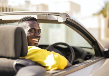 black man driving car turning around to smile