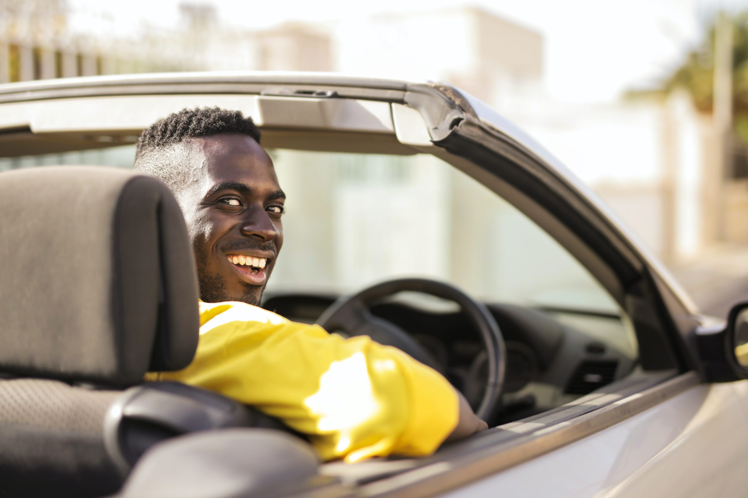 black man driving car turning around to smile