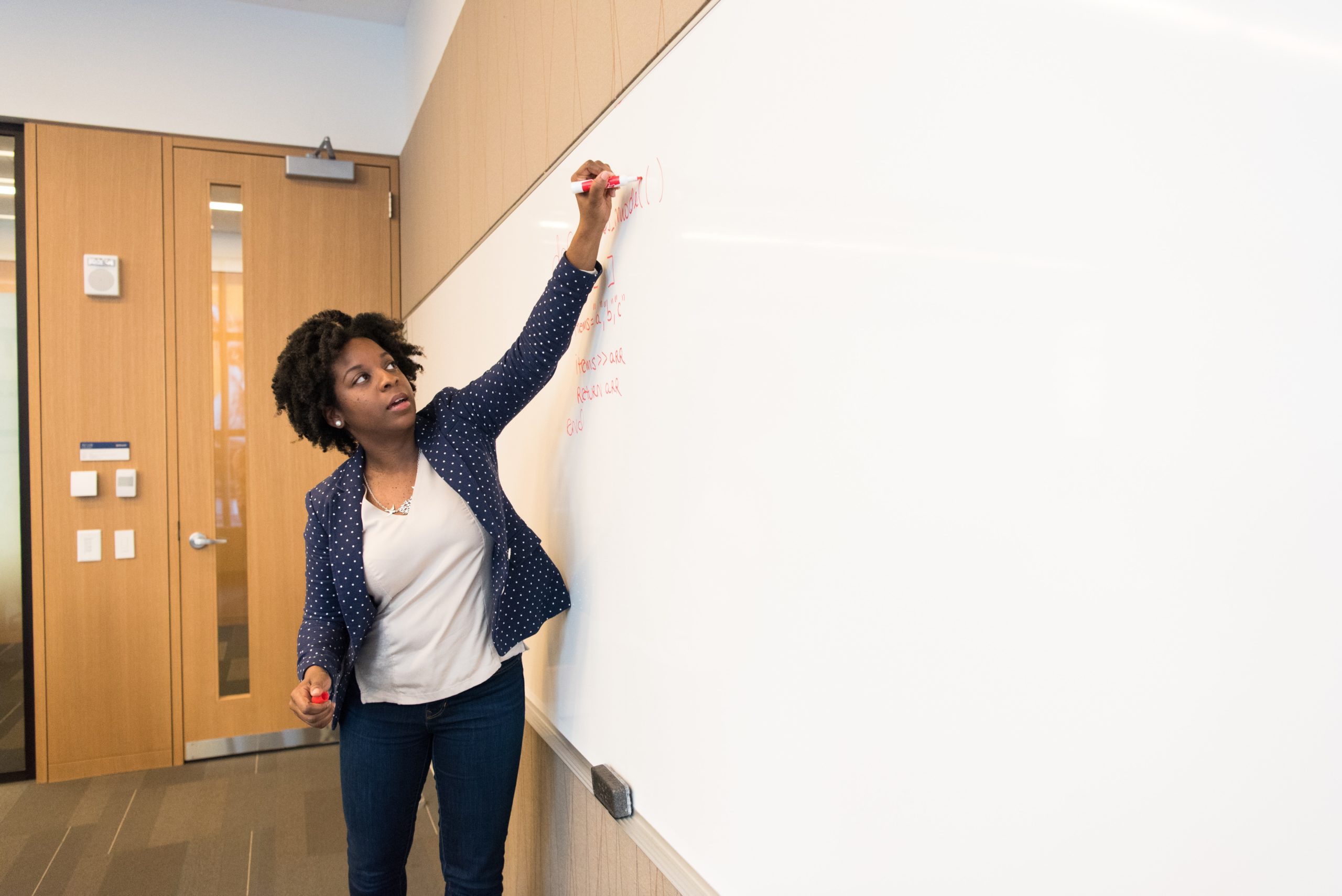 black woman teacher writing on whiteboard