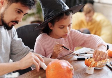 girl and dad decorating pumpkins for halloween