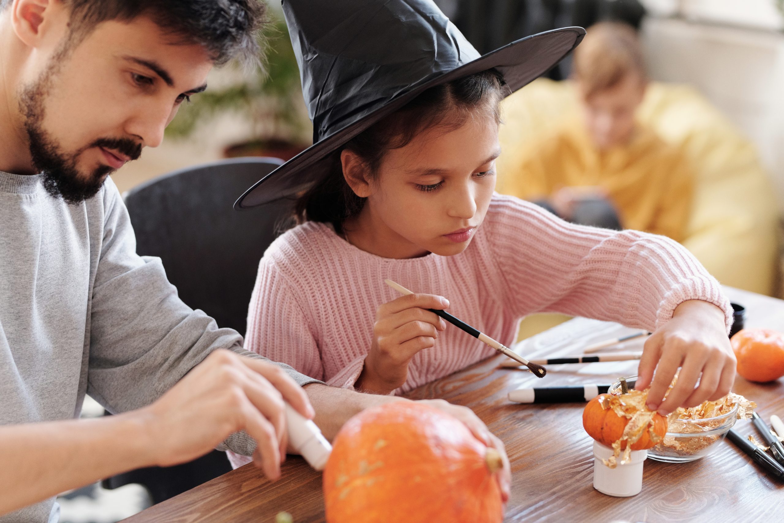 girl and dad decorating pumpkins for halloween