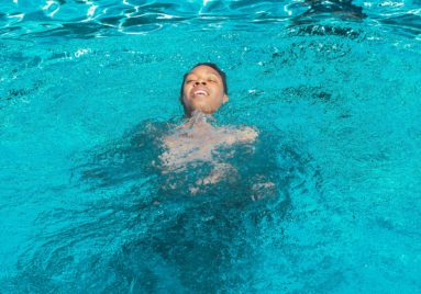 person swimming in pool on their back with head above water