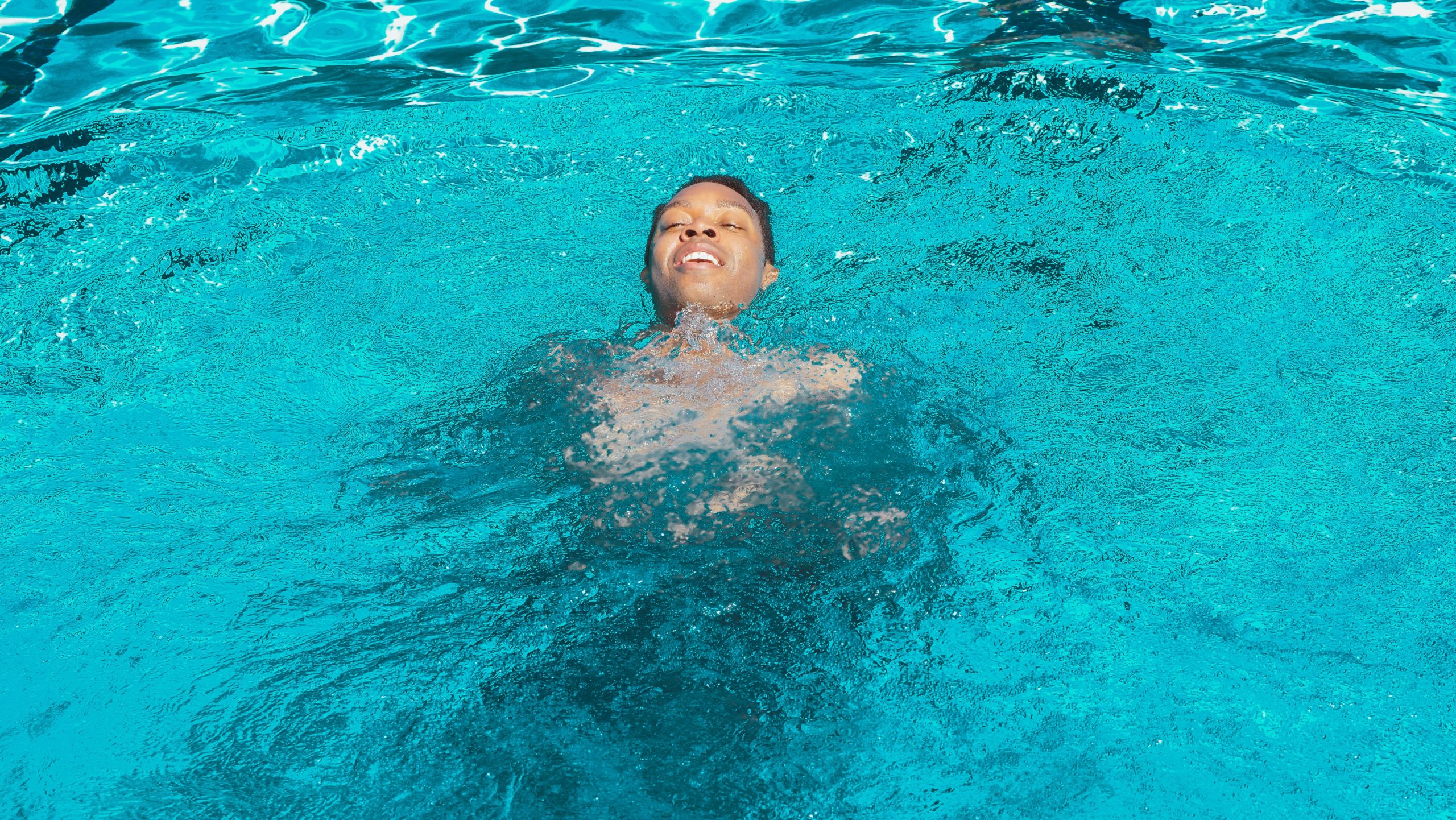 person swimming in pool on their back with head above water