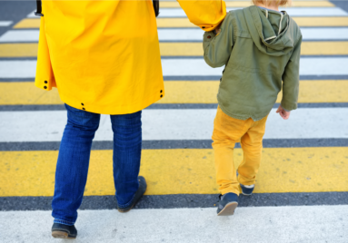 parent holding child's hand walking them across the street in a crosswalk, child safety tips