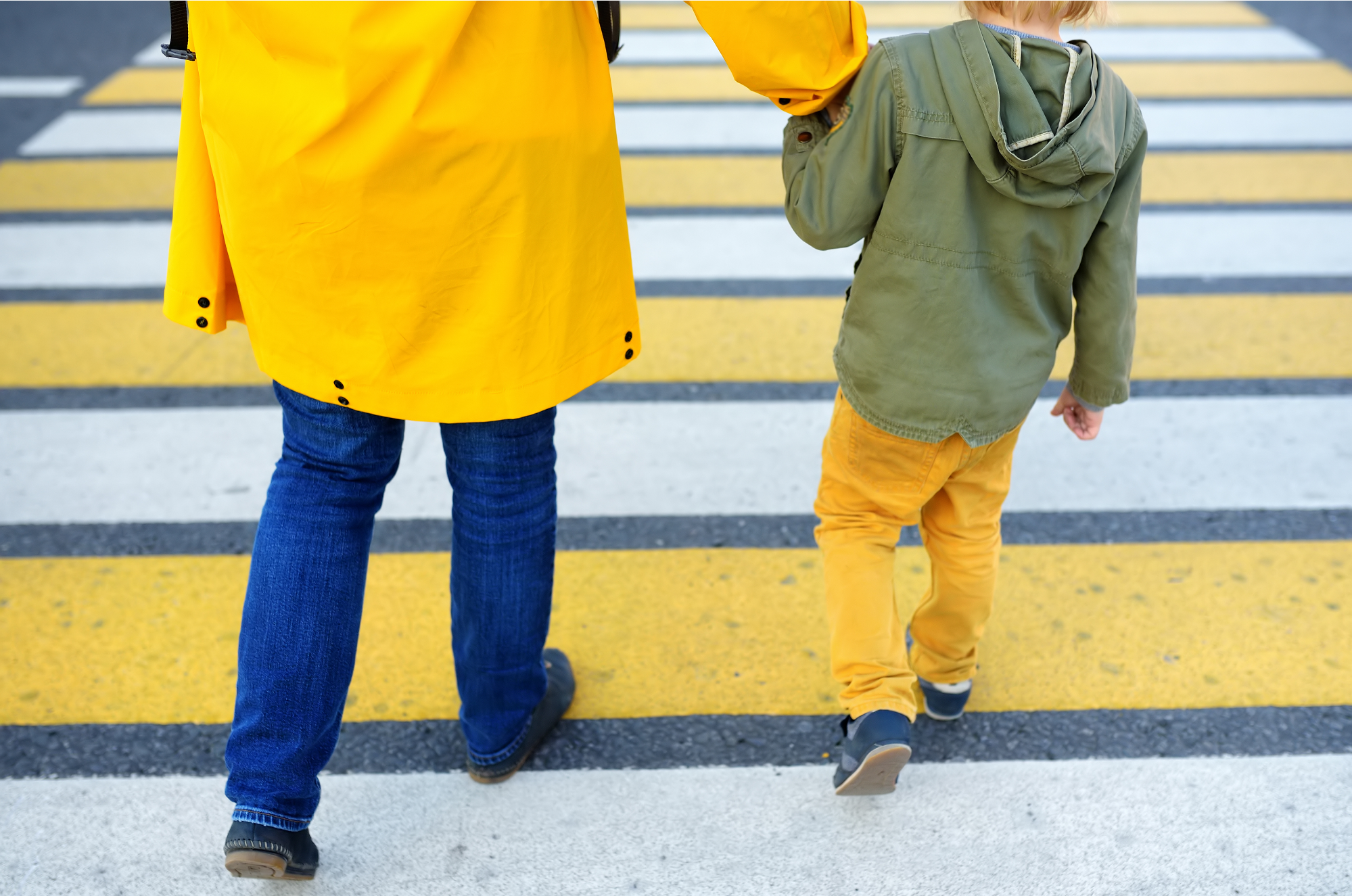 parent holding child's hand walking them across the street in a crosswalk, child safety tips