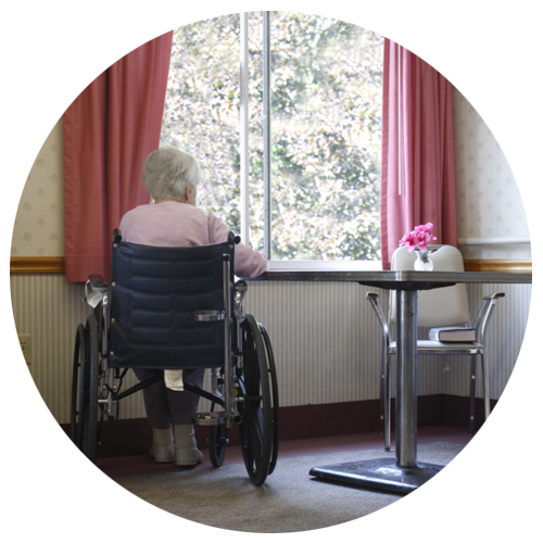 old person sitting in a wheel chair near a window