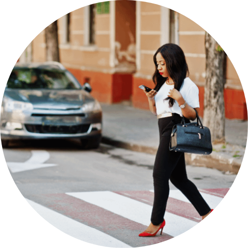 Lawyers in East Point, GA-woman with shoulder-length dark hair crosses a street while looking at her phone. 