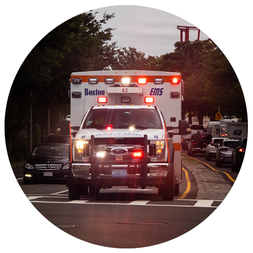 An ambulance drives down a road with its emergency lights flashing