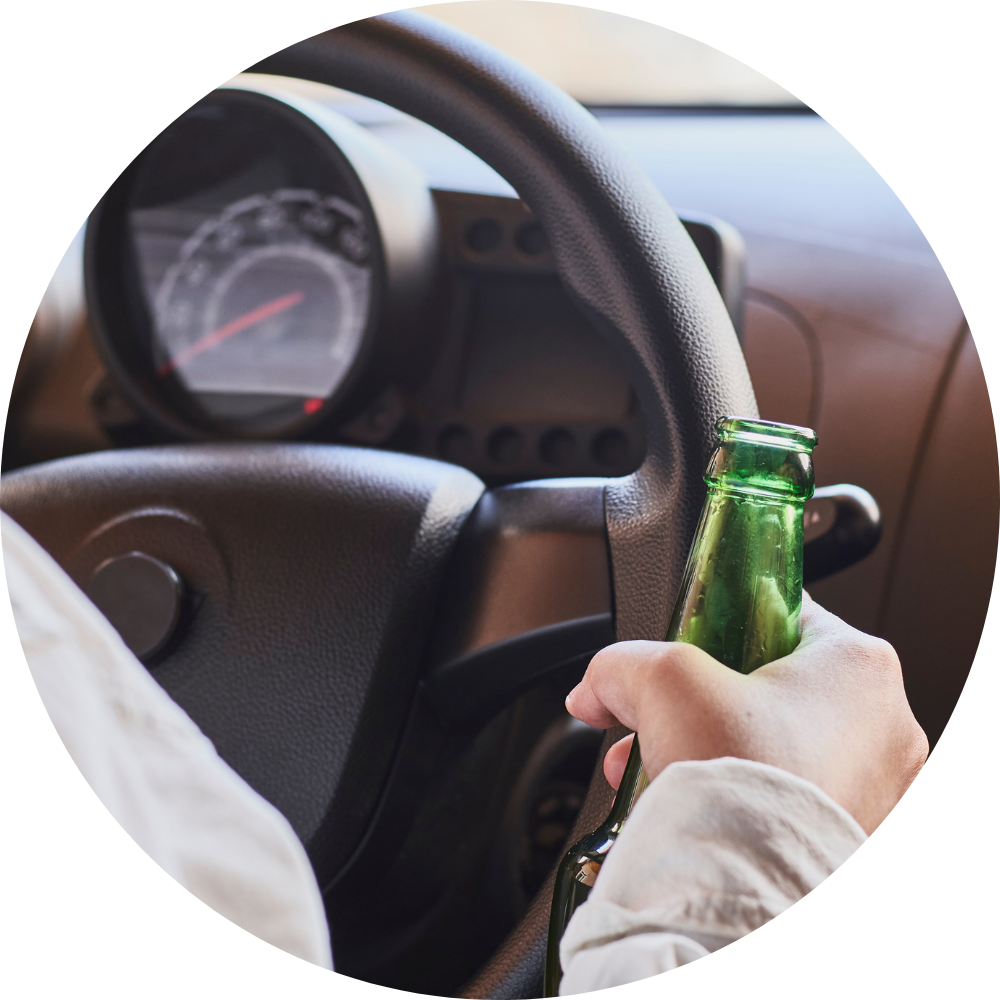 a person driving a car with a beer in their hand next to the steering wheel