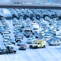 Snow and ice car accident on an Atlanta highway with multiple vehicles and emergency responders assisting drivers.